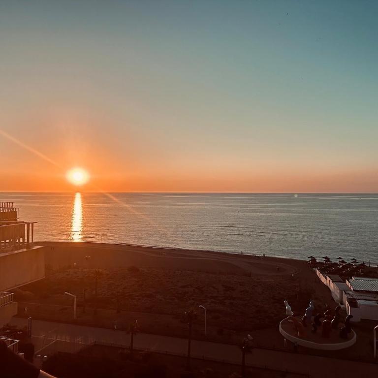 - un coucher de soleil sur l'océan avec un groupe de personnes dans l'établissement Face à la mer, au Barcarès