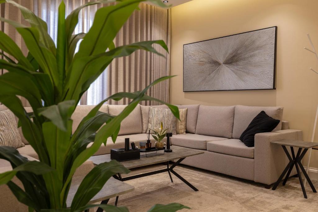 Una sala de estar con un sofá y una planta. en شقه 3فاخره ثلاث غرف نوم, en Riad