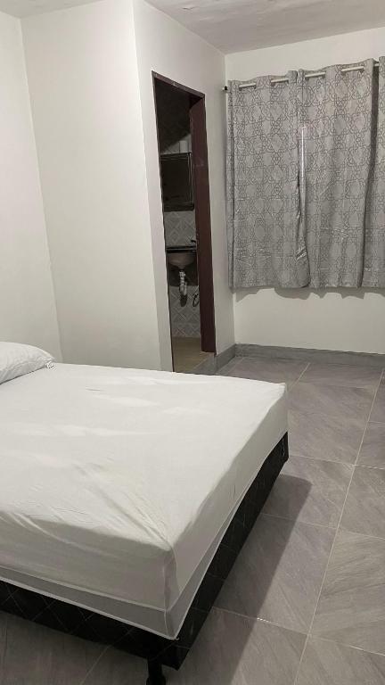 a white bed in a room with a window at hotel viena da serra in Luziânia