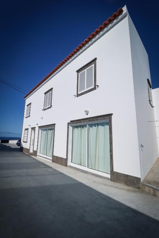 a white building with glass windows on the side of it at Casa do Parque in Rabo de Peixe