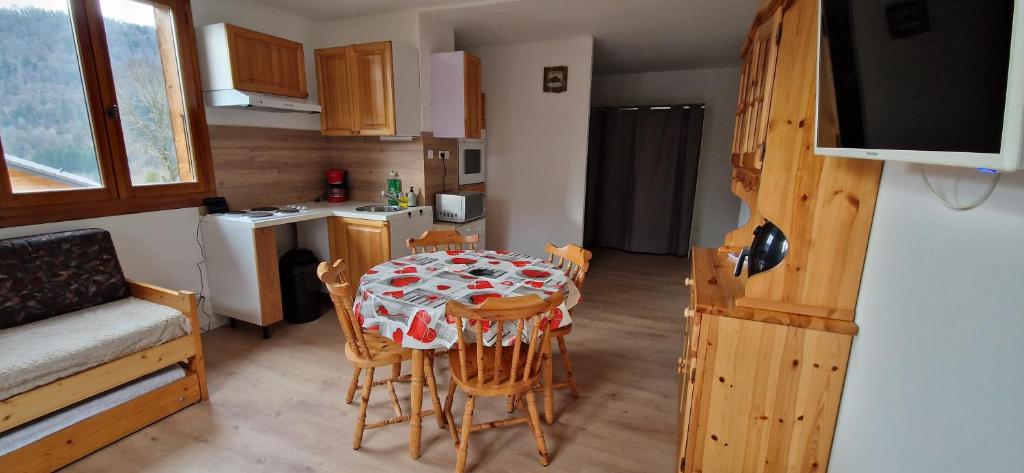 une cuisine avec une table et des chaises dans une pièce dans l'établissement Grand studio montagnard, à Mieussy
