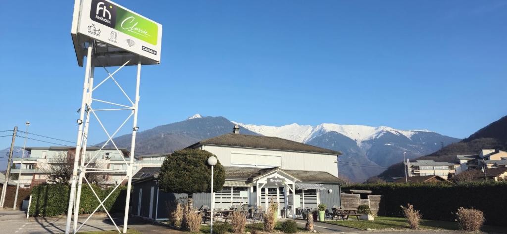 una señal frente a una casa con montañas en el fondo en Fasthotel Albertville, en Albertville