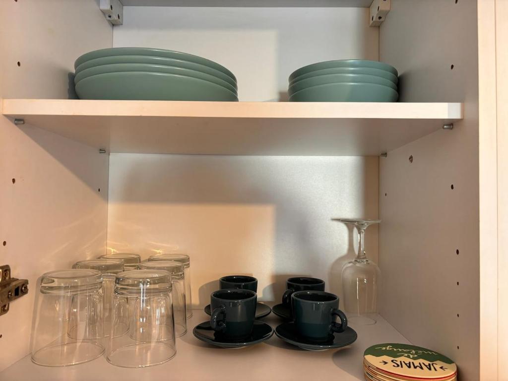 une étagère avec des bols et des plats en verre dessus dans l'établissement Sun Secondo - Piccolo Monolocale nel Centro di Torino, à Turin