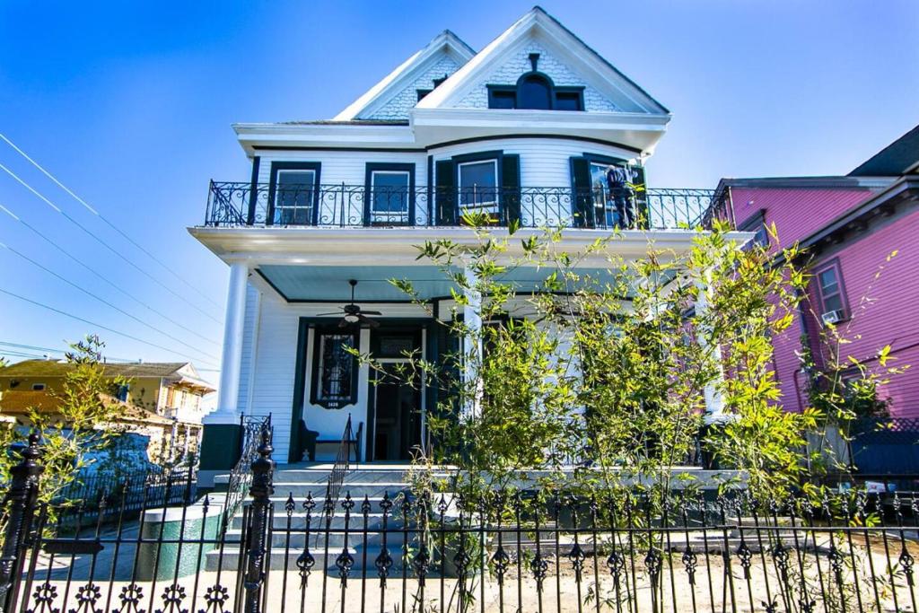 a white house with a fence in front of it at Claiborne Historic Mansion - 5 bed-3bath in New Orleans