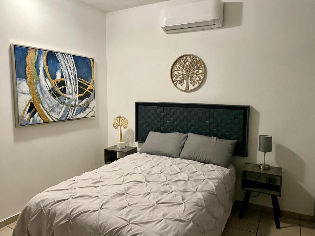 ein Schlafzimmer mit einem Bett und einem Gemälde an der Wand in der Unterkunft Agradable depto con estacionamiento y portón eléctrico in Guasave