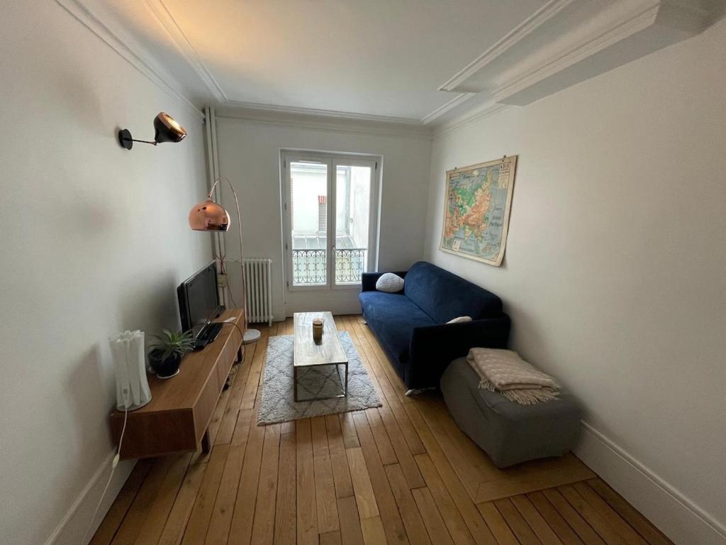un salon avec un canapé bleu et une télévision dans l'établissement Charming and bright flat in a very convenient area, à Paris