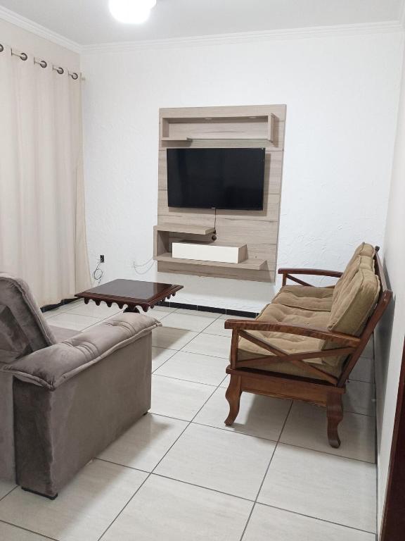 a living room with two chairs and a television at Refúgio verde in Itatiaia