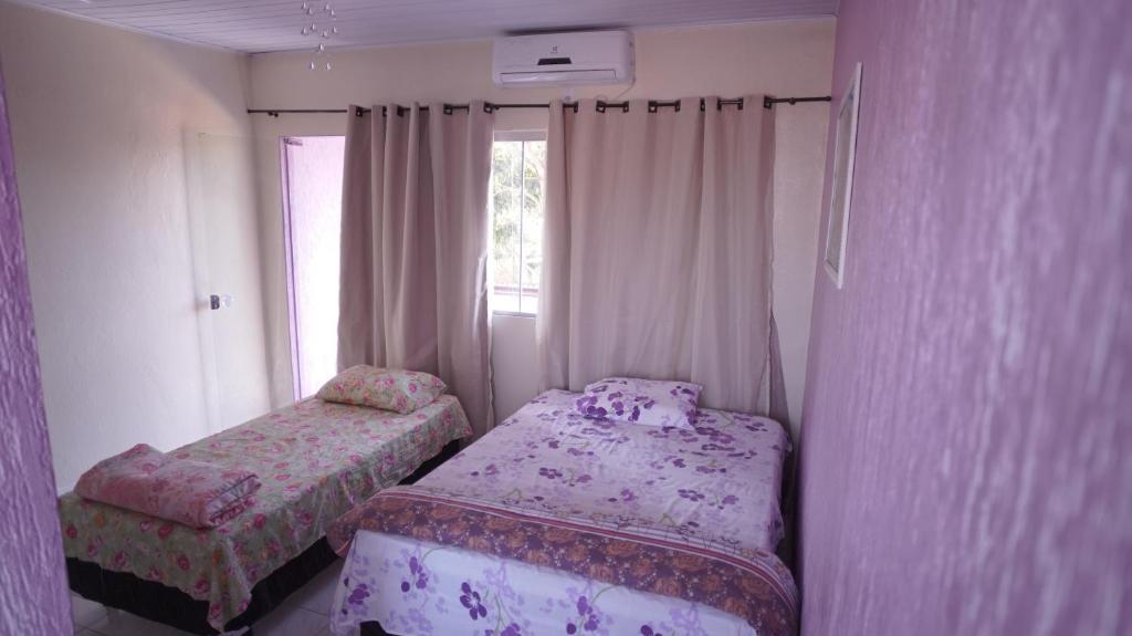 a small bedroom with two beds and a window at Pousada Centaurus in Alto Paraíso de Goiás
