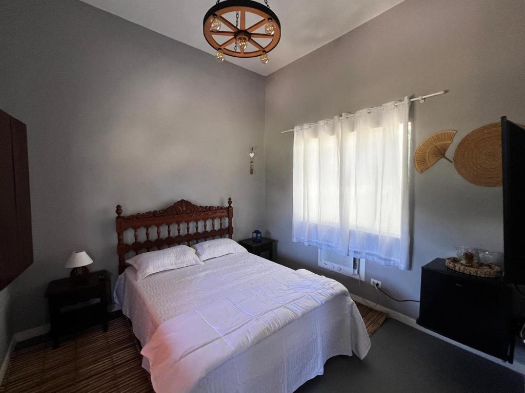 une chambre avec un lit blanc avec une fenêtre dans l'établissement Fazenda Raiz da Serra, à Itaguaí