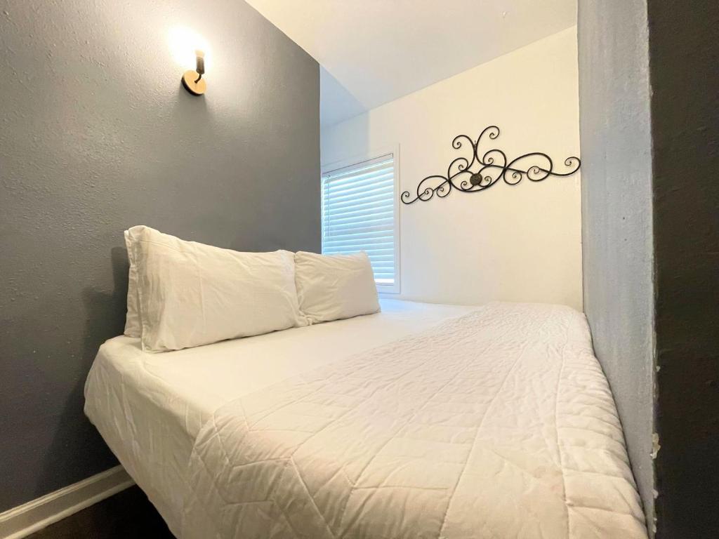 een bed met witte lakens en een licht aan de muur bij Mangosteen in New Orleans