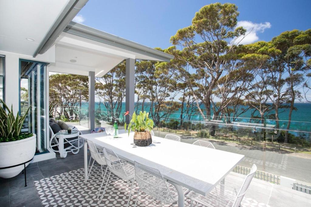 a dining room with a white table and views of the ocean at 5 BDR - 250m to Beach - Outdoor Spa - 4PM Checkout in Hyams Beach