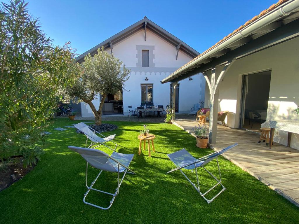 une cour avec des chaises et une table ainsi qu'une maison dans l'établissement Charmante maison Arcachonnaise, 4 chambres, 300m de la plage - FR-1-374-231, à Arcachon