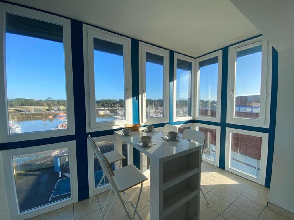 une pièce avec une table, des chaises et des fenêtres dans l'établissement Appartement spacieux à Capbreton avec terrasse, animaux acceptés, parking sécurisé - FR-1-413-253, à Capbreton