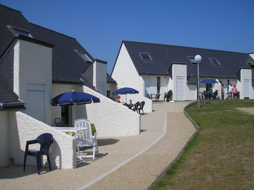 een groep stoelen en tafels met parasols op een stoep bij KER-AR-MOR Village Vacances in Le Pouldu