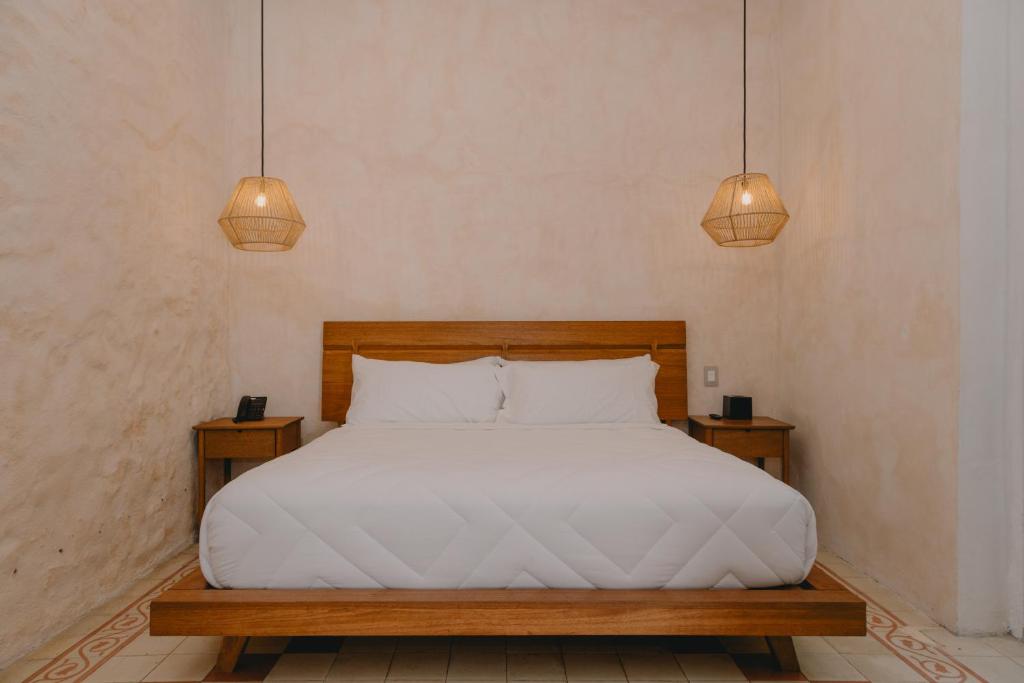 a bedroom with a bed with two night stands and two lights at Hotel Boutique Casa Yága in Querétaro