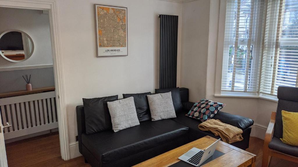 Una sala de estar con un sofá de cuero negro y una mesa. en Victoria House, en Exeter