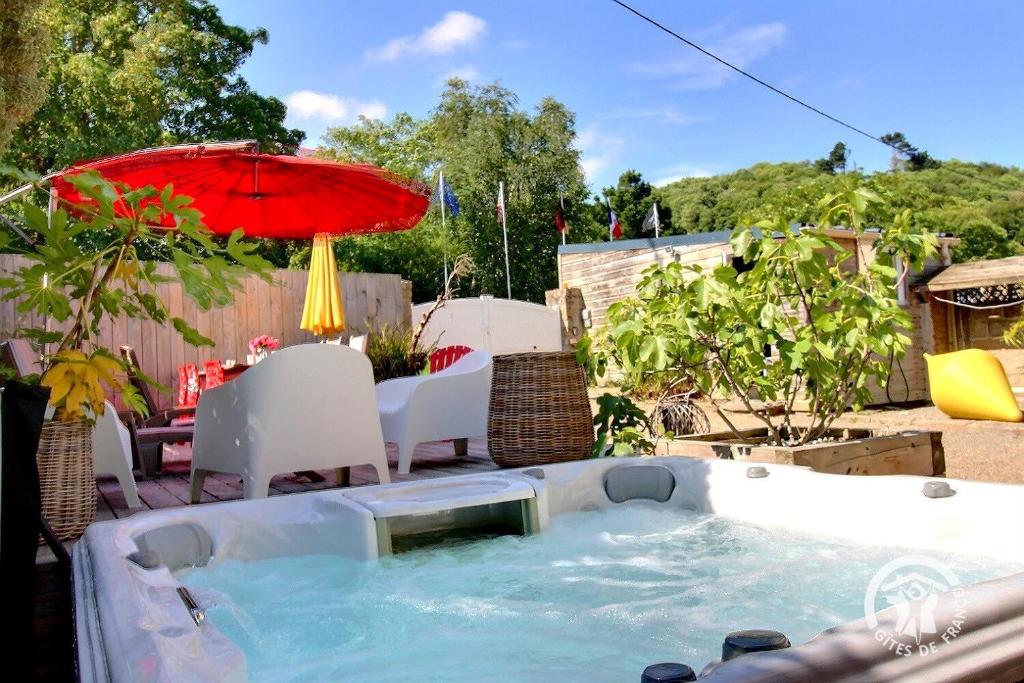 a hot tub in a backyard with an umbrella at La villa de la lieue de greve in Plestin-les-Grèves