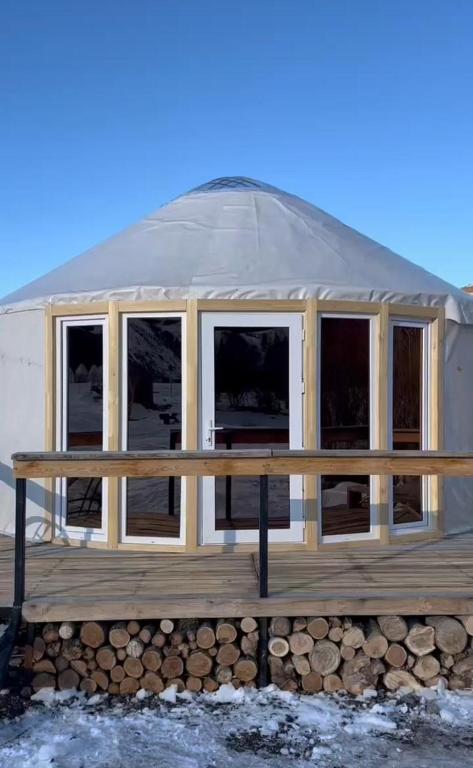 a yurt with windows on a wooden deck at Отдых в комфортабельных юртах в зоне отдыха Kolsay resort! in Kurmenty