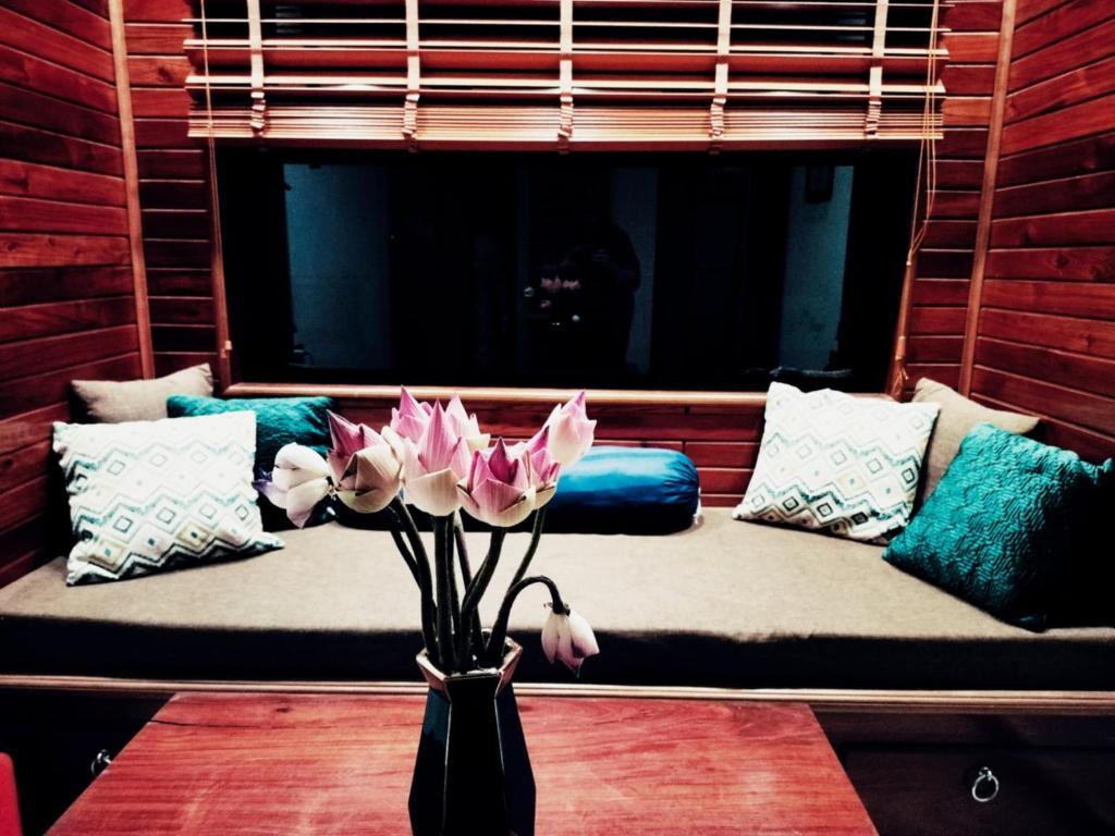 a vase with flowers on a table in front of a couch at Baksaei Retreat Ricefield Villas in Kampot