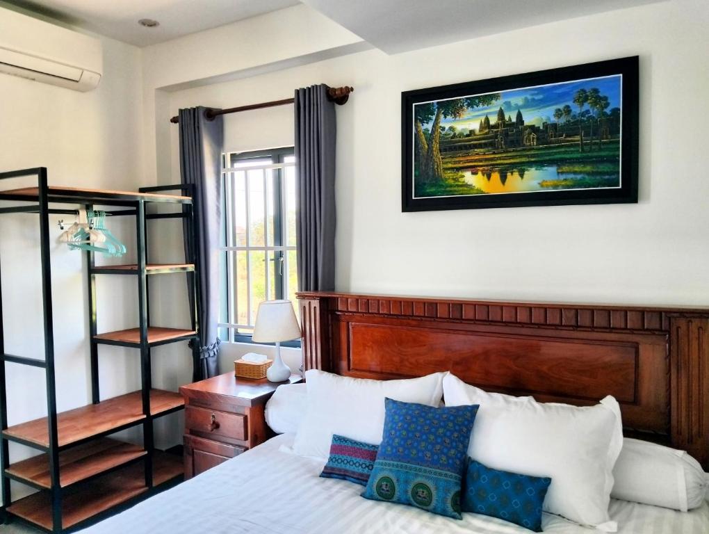 a bedroom with a bed with blue and white pillows at Baksaei Retreat Ricefield Villas in Kampot