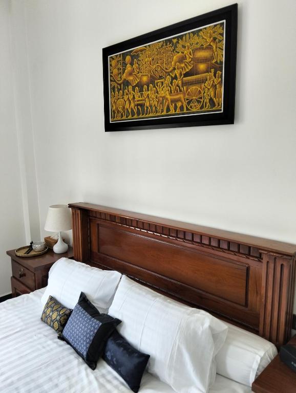 a bed with a wooden headboard and a picture on the wall at Baksaei Retreat Ricefield Villas in Kampot