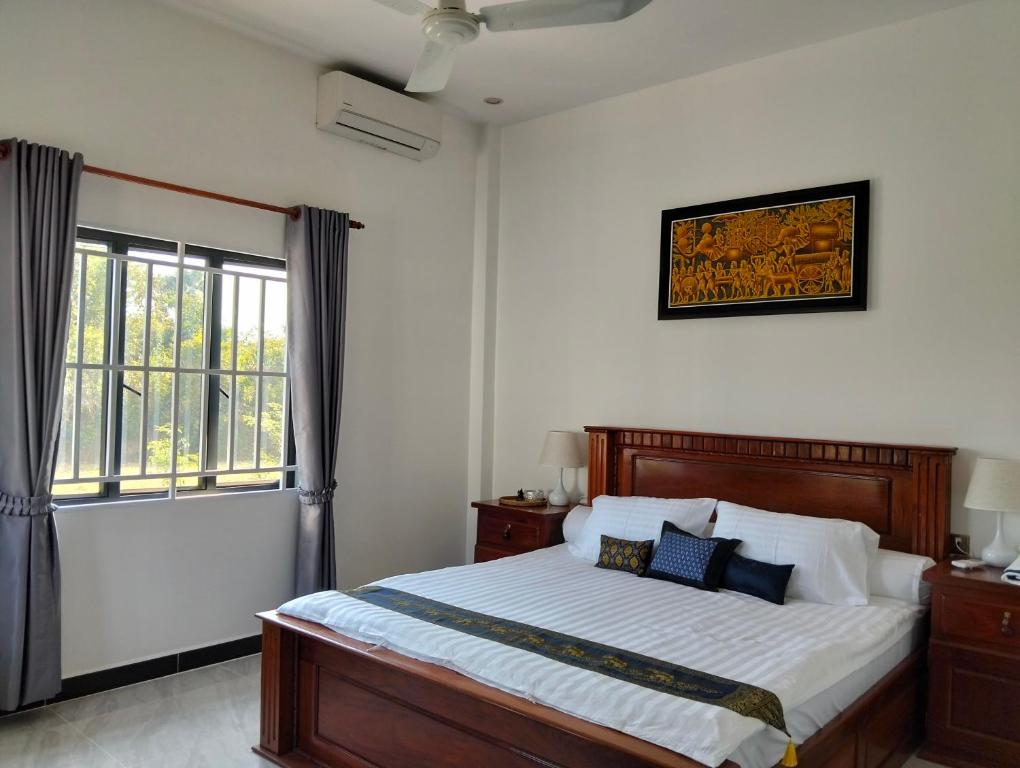 a bedroom with a large bed and a window at Baksaei Retreat Ricefield Villas in Kampot