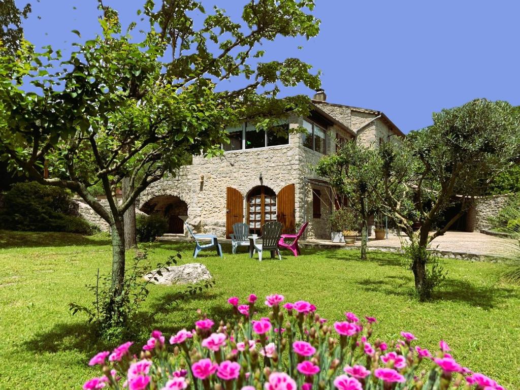 une maison avec des fleurs roses dans la cour dans l'établissement La Peireta-Romantique, à Saint Alban Auriolles