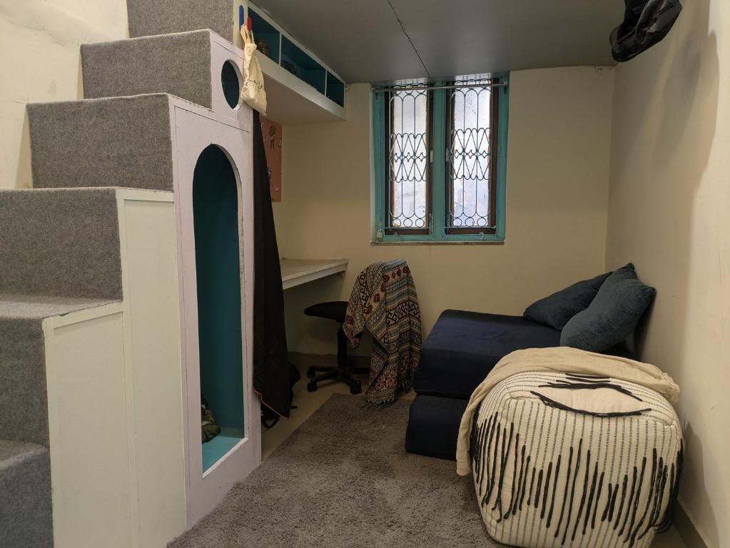 Zimmer mit einer Treppe, einem Bett und einem Sofa in der Unterkunft Serendipity Hostel & Cats Cafe in Rishikesh
