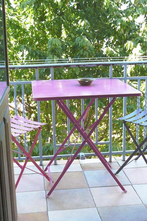 une table rose et deux chaises sur un balcon dans l'établissement Grand meublé 70 m2 centre-ville proche lac, à Annecy