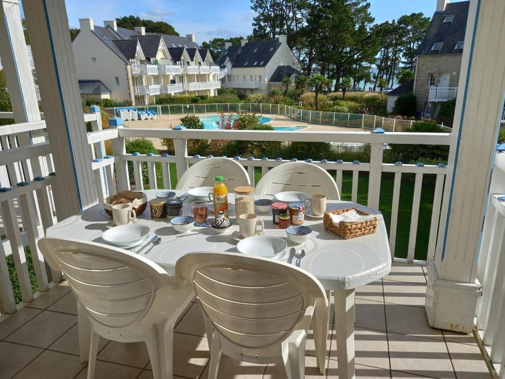 a white table and chairs on a balcony with a view at A11 - appartement vue mer avec piscine in Fouesnant