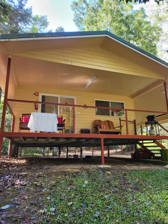 a screened in porch with a large picnic table in front of a house at Chilverton Cottages in Ravenshoe