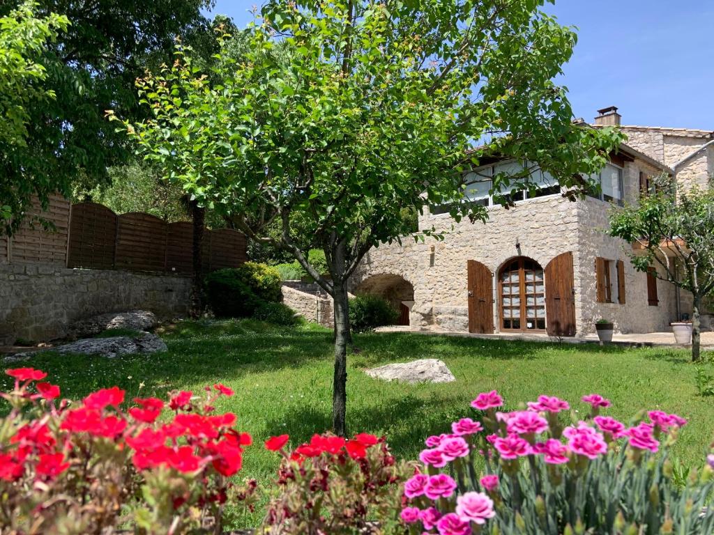 un jardin avec des fleurs roses en face d'une maison dans l'établissement La Peireta-Authentique, à Saint Alban Auriolles