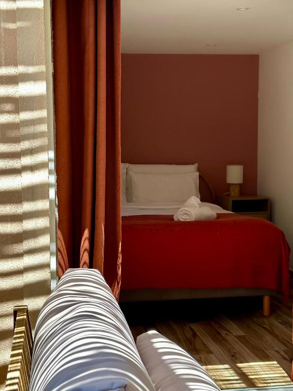 a bedroom with a red bed and a window at Hôtel Palombaggia in Porto-Vecchio