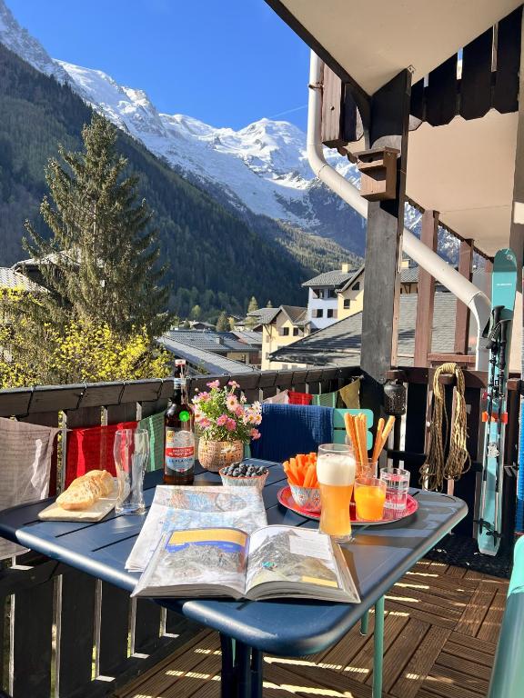 - une table sur un balcon avec un livre et des boissons dans l'établissement Le Petit Cham, à Chamonix-Mont-Blanc
