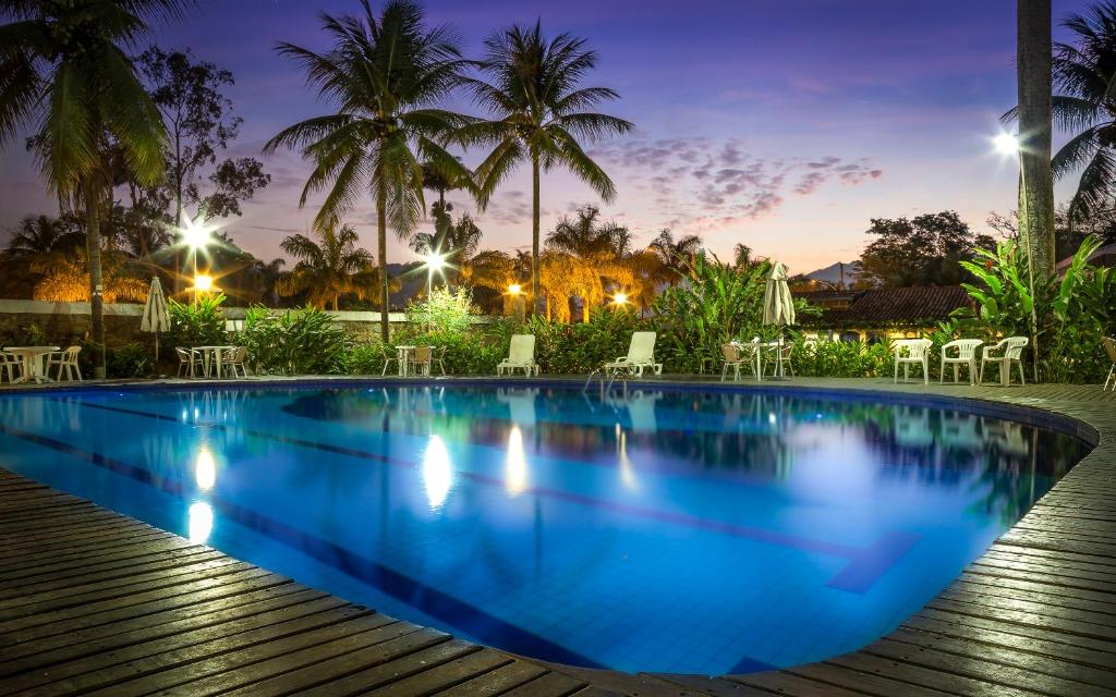 a swimming pool at night with chairs and palm trees at Pousada da Condessa in Paraty