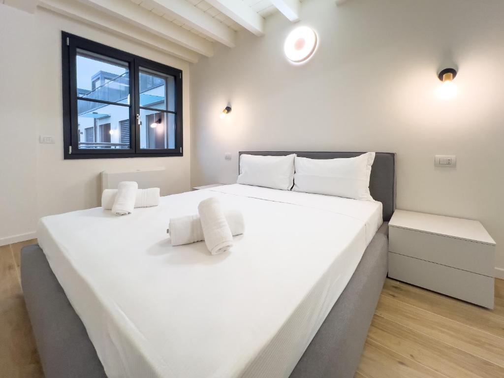 a large white bed in a room with a window at Bright apartment with terrace and pool in Milan