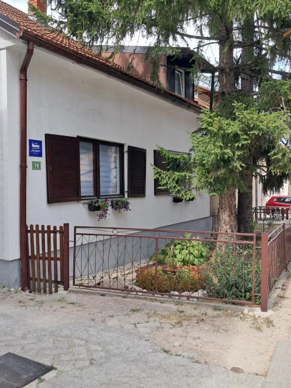 a white house with a fence and a tree at Apartman Mario in Bihać