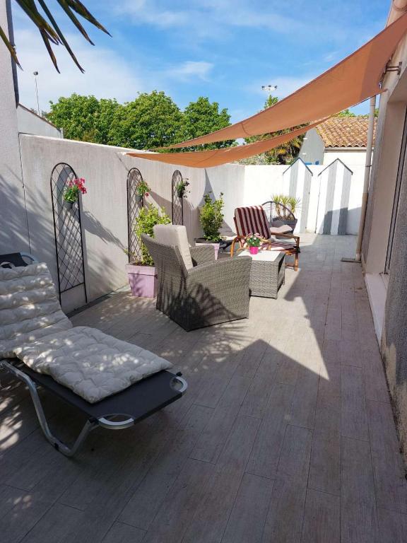 une terrasse avec des chaises, des tables et un parasol dans l'établissement Maison 3 pièces 5 couchages Saint Pierre d'Oléron SPO000-329, à Saint-Pierre-dʼOléron