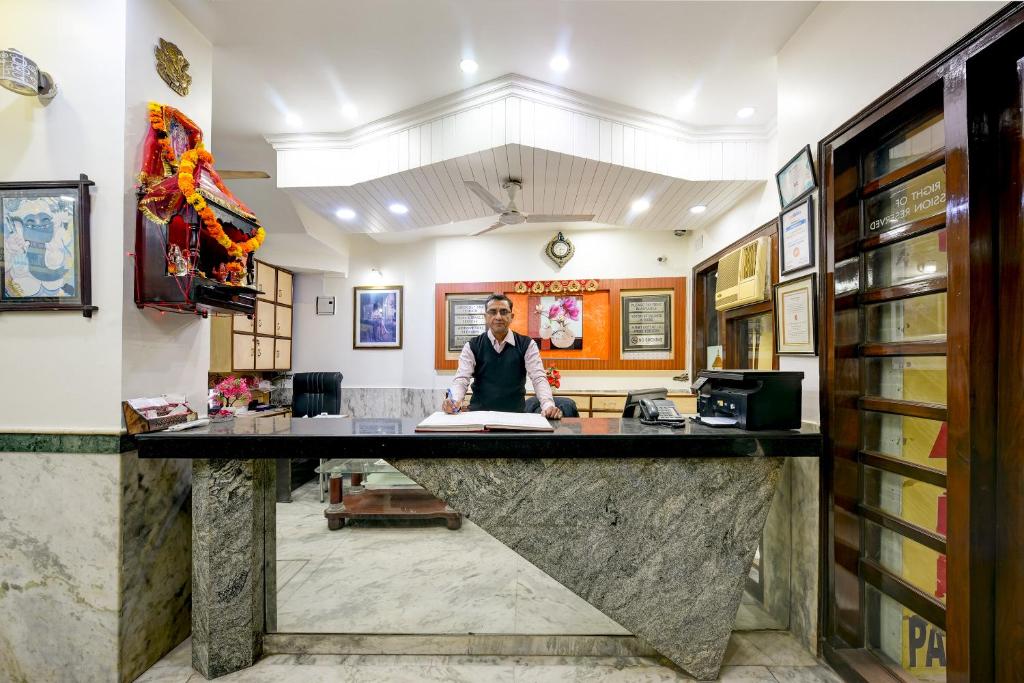 a man standing behind a counter in a room at Hotel Paradise - New Delhi in New Delhi