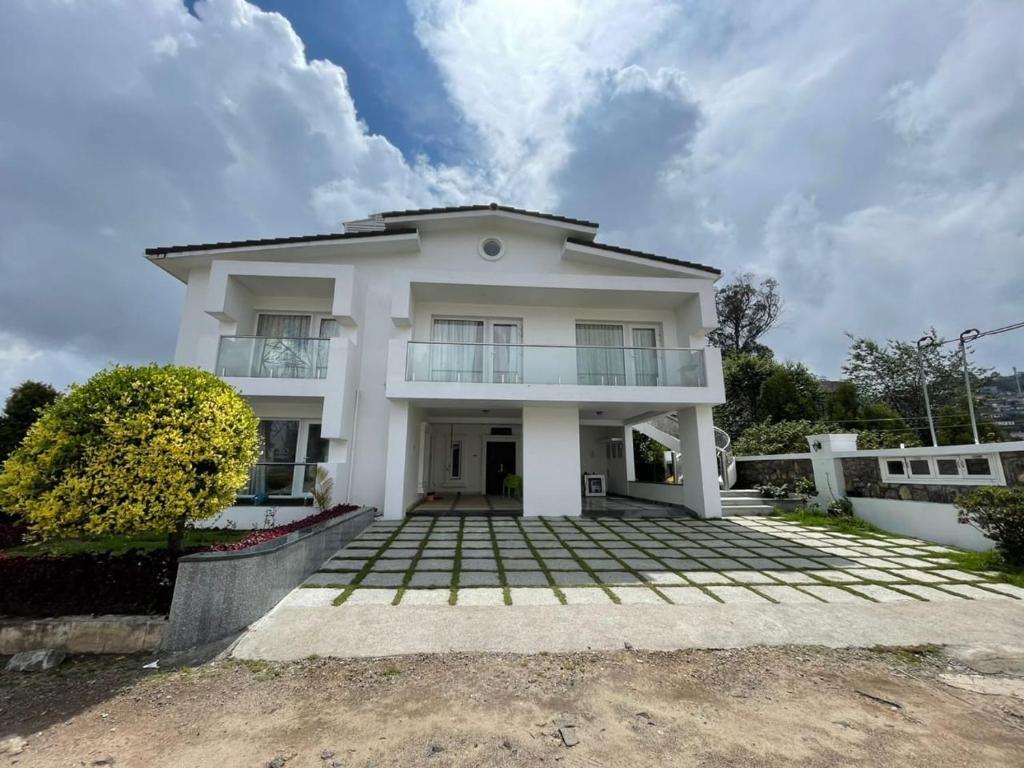 ein weißes Haus mit großer Auffahrt in der Unterkunft Cloud Nine Kodai, Family Only Boutique Home Stay in Kodaikanal