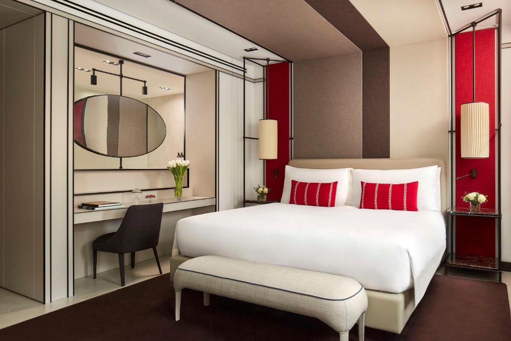 a bedroom with a white bed with red pillows and a desk at Tivoli Portopiccolo Sistiana Wellness Resort & Spa in Sistiana