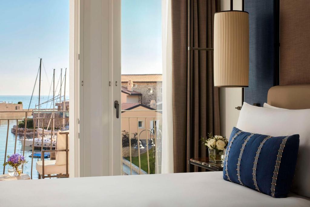 a hotel room with a bed and a large window at Tivoli Portopiccolo Sistiana Wellness Resort & Spa in Sistiana