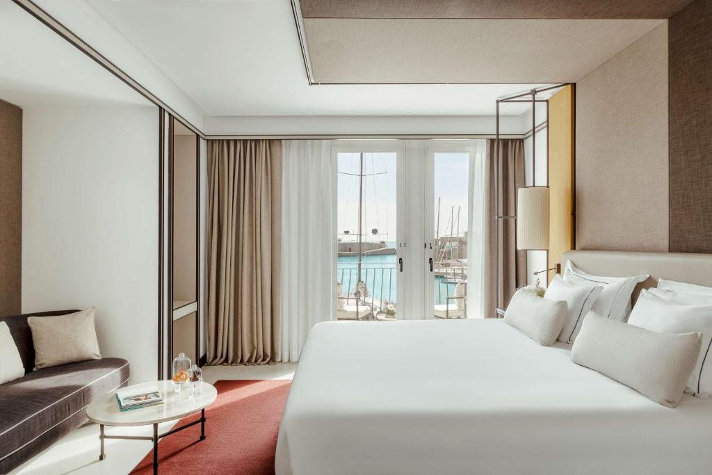 a bedroom with a large white bed and a couch at Tivoli Portopiccolo Sistiana Wellness Resort & Spa in Sistiana