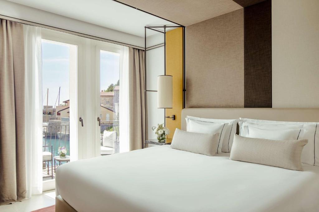 a bedroom with a large white bed and a large window at Tivoli Portopiccolo Sistiana Wellness Resort & Spa in Sistiana