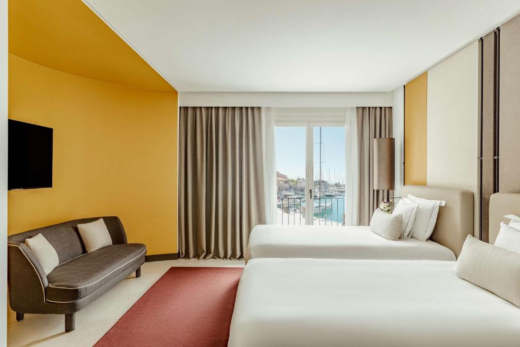 a hotel room with two beds and a chair at Tivoli Portopiccolo Sistiana Wellness Resort & Spa in Sistiana