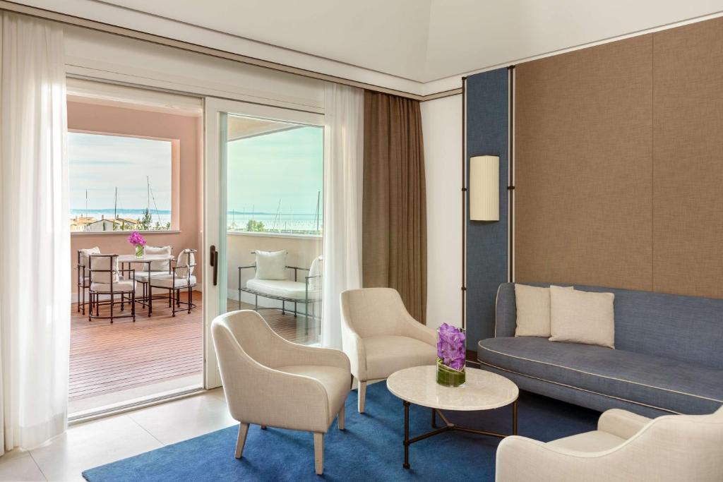 a living room with a couch and a table with chairs at Tivoli Portopiccolo Sistiana Wellness Resort & Spa in Sistiana