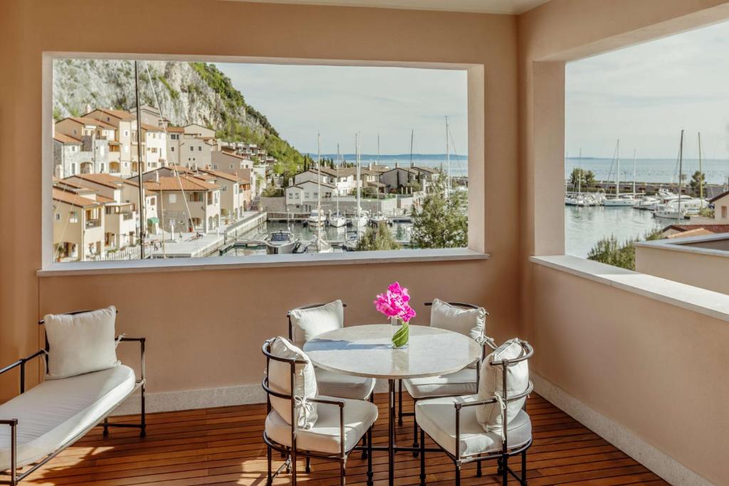 a dining room with a table and chairs and a large window at Tivoli Portopiccolo Sistiana Wellness Resort & Spa in Sistiana