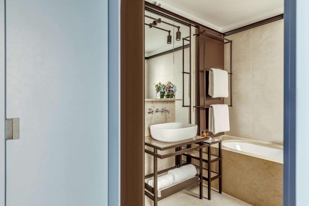 a bathroom with a tub and a sink and a bath tub at Tivoli Portopiccolo Sistiana Wellness Resort & Spa in Sistiana