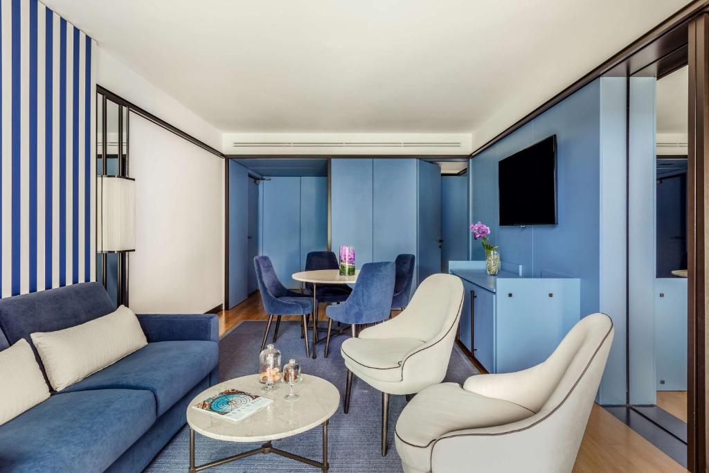 a living room with a blue couch and chairs and a table at Tivoli Portopiccolo Sistiana Wellness Resort & Spa in Sistiana