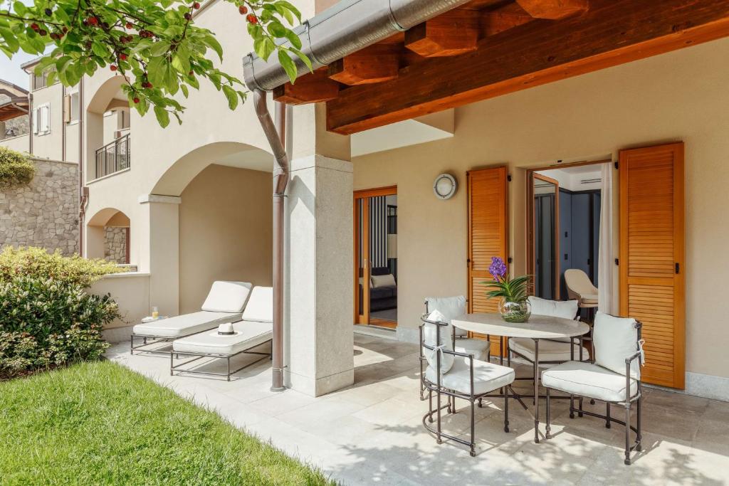 a patio with a table and chairs in a yard at Tivoli Portopiccolo Sistiana Wellness Resort & Spa in Sistiana
